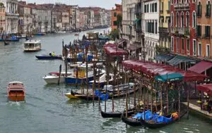 Real photograph of Venice's Grand Canal near Rialto Bridge on a rainy day, with boats and wet waterfront