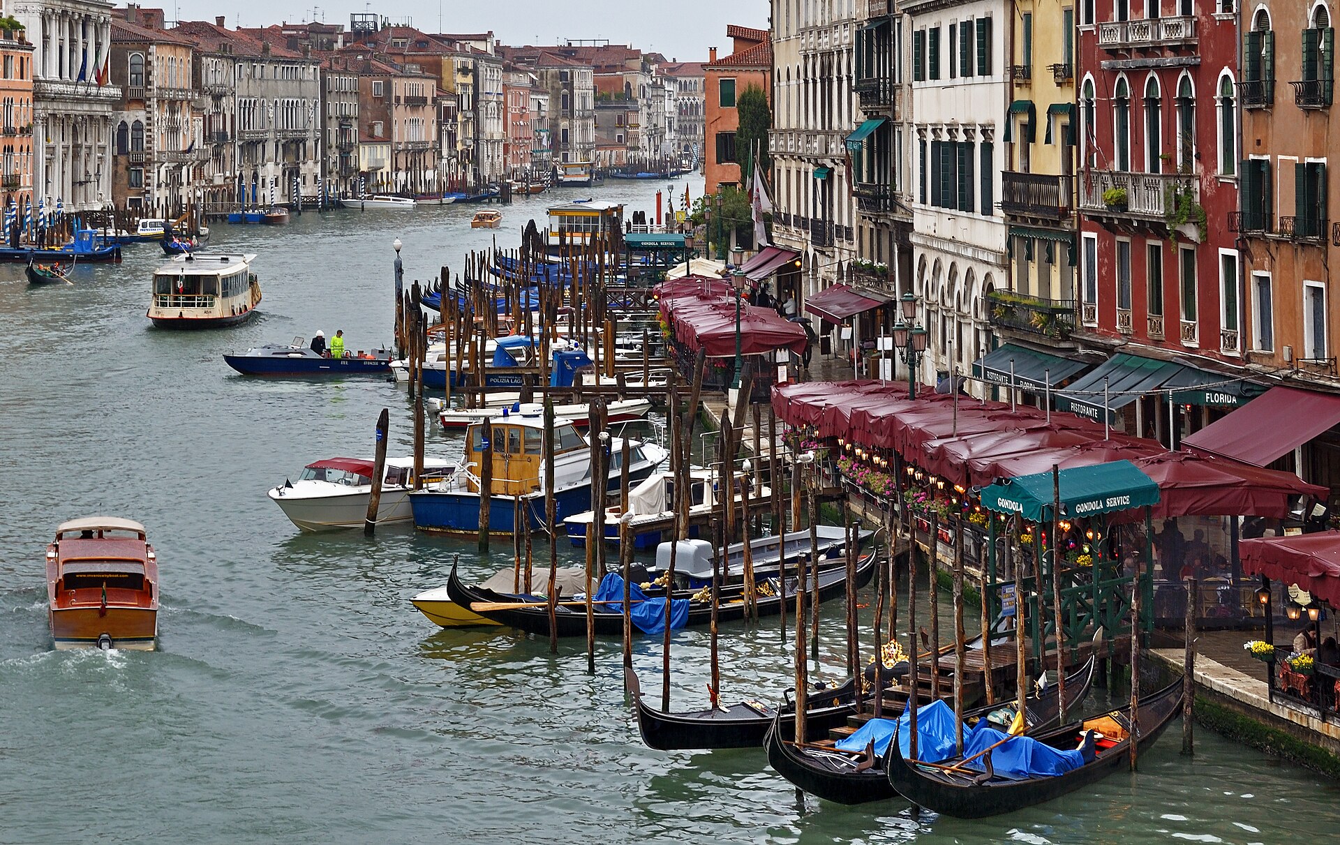 Real photograph of Venice's Grand Canal near Rialto Bridge on a rainy day, with boats and wet waterfront