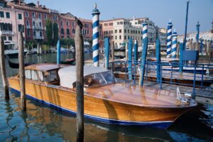 Classic wooden Venetian motorboat cruising along the Grand Canal near Rialto Bridge, a private way to explore Venice