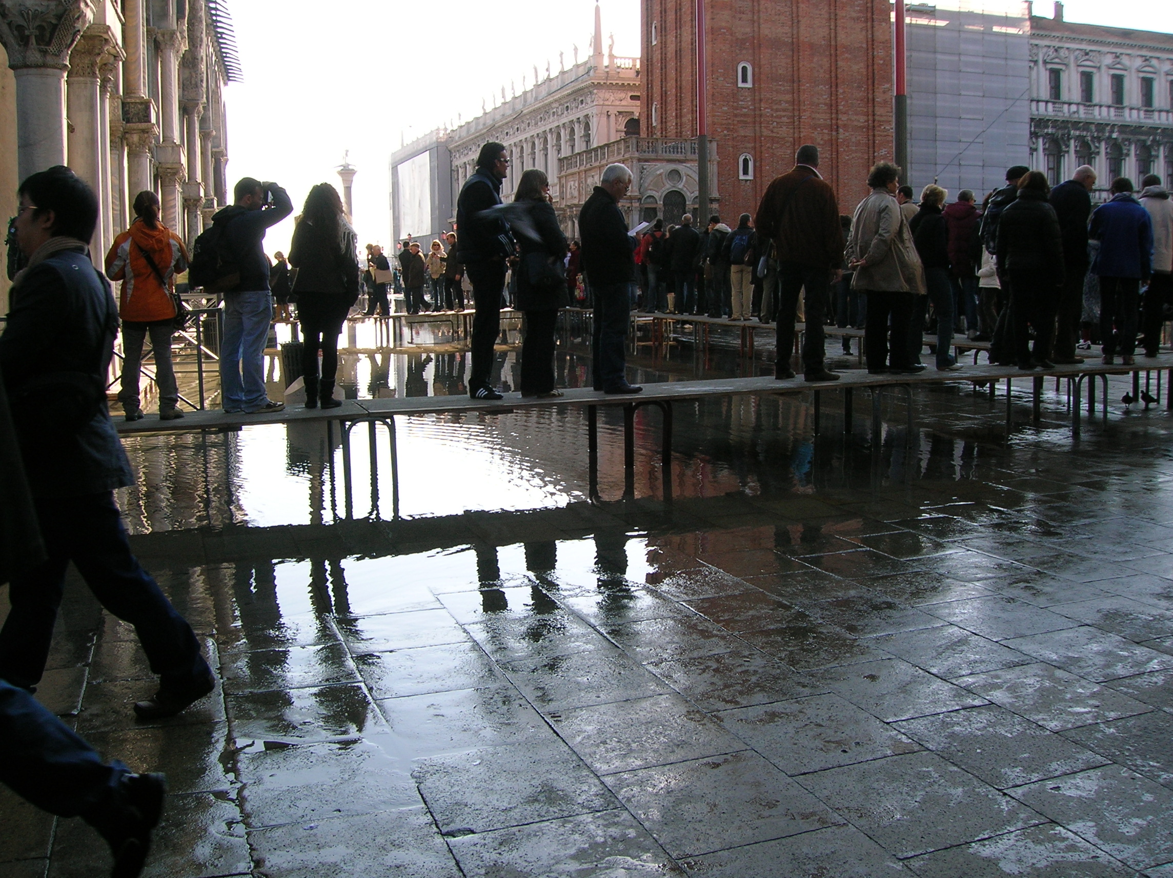 Authentic photograph of visitors using raised pedestrian walkways during acqua alta near St Mark's Basilica in Venice